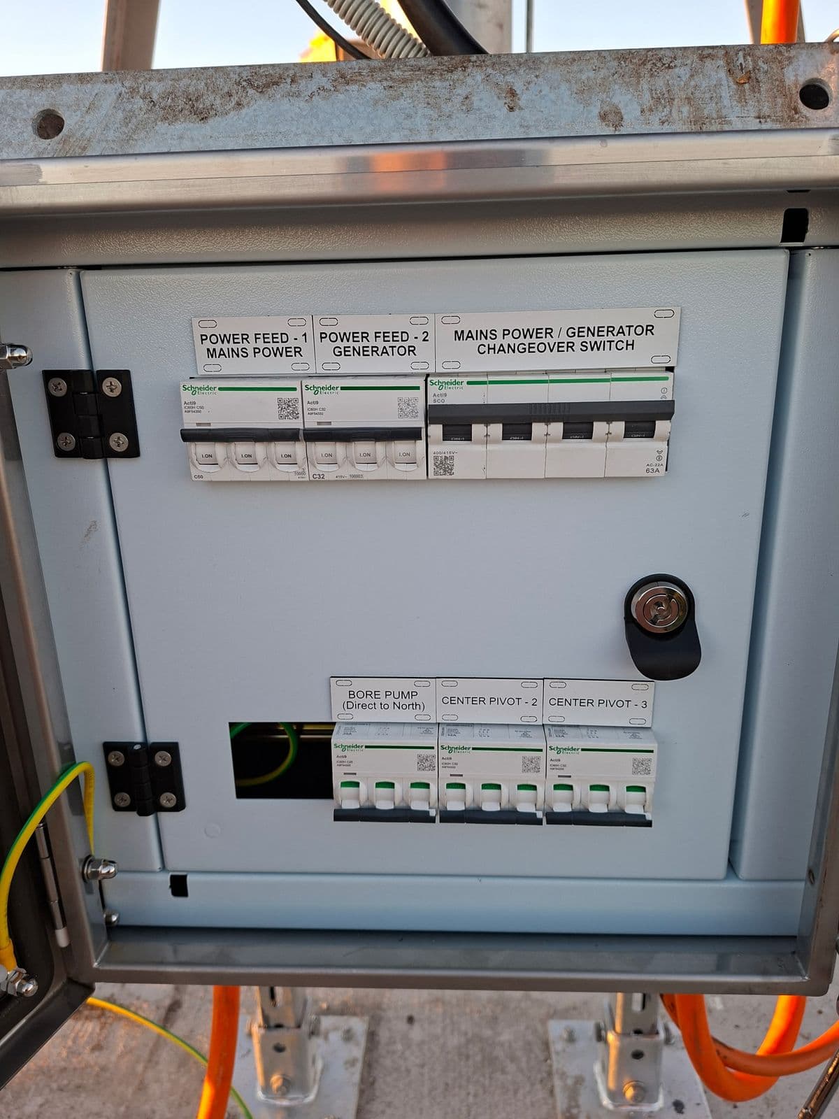 Open rural distribution switchboard with engraved white circuit labels above the breakers