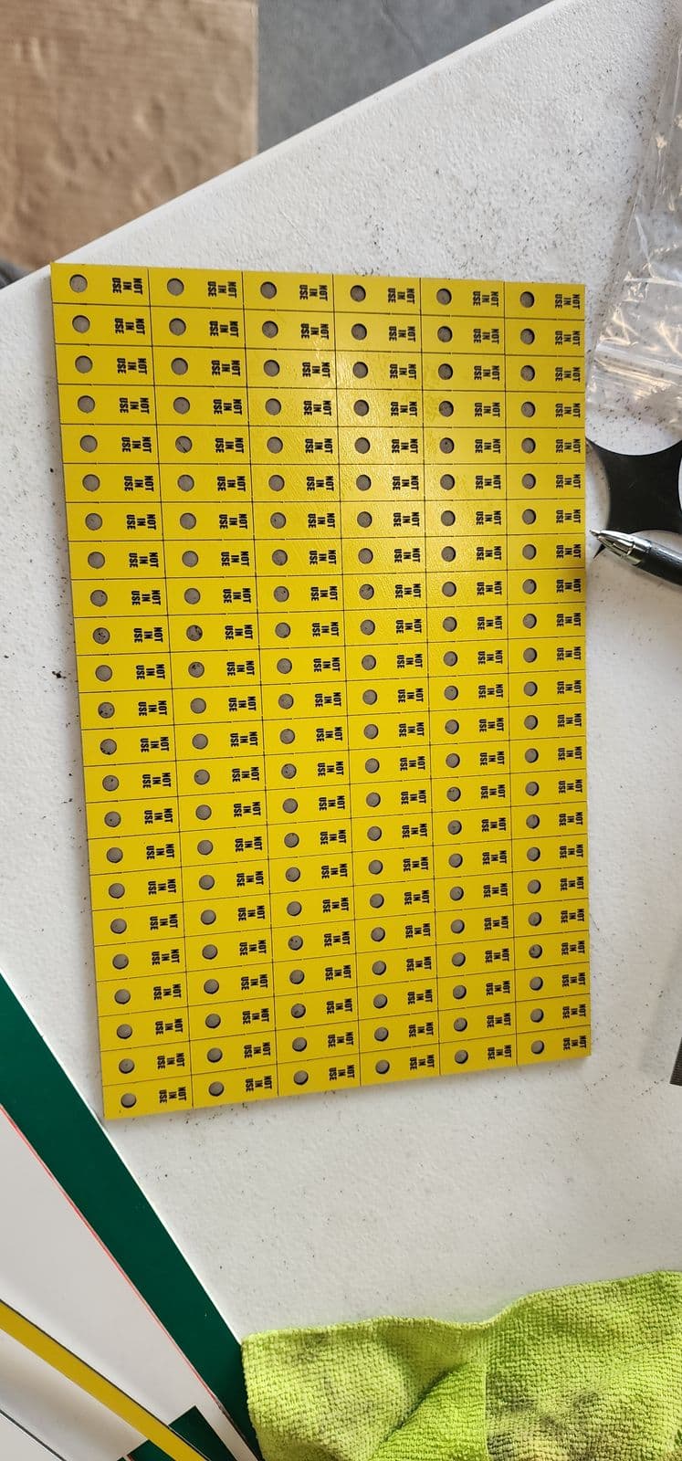 Large sheet of yellow traffolyte Not In Use tags with mounting holes, dozens cut in a single production run