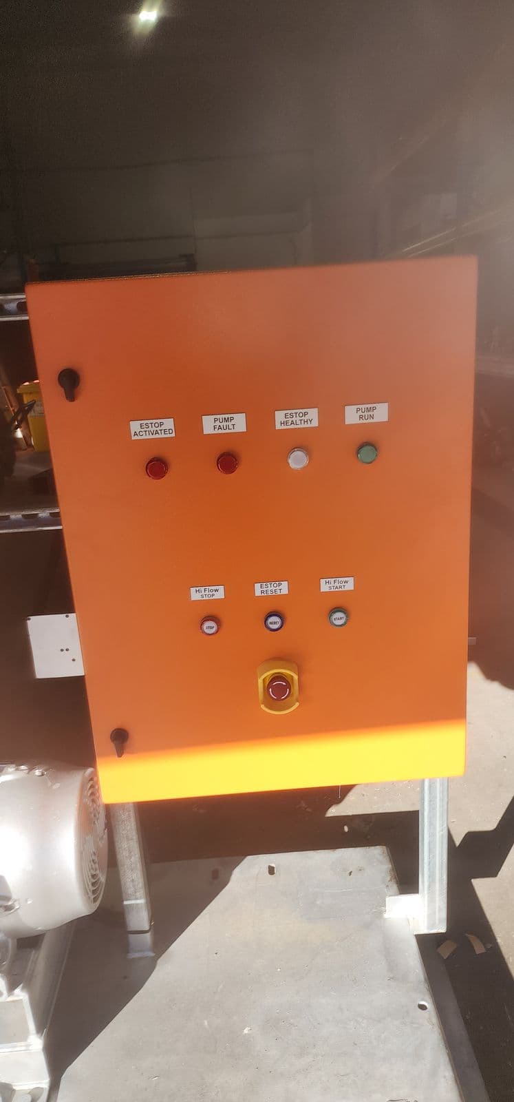 Orange industrial pump control panel with white traffolyte labels installed above buttons and indicator lights