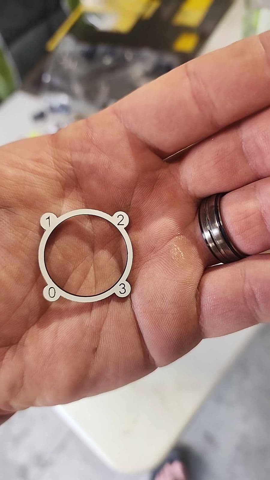 Small grey traffolyte selector surround plate marked 0, 1, 2, 3 held in an open palm for scale