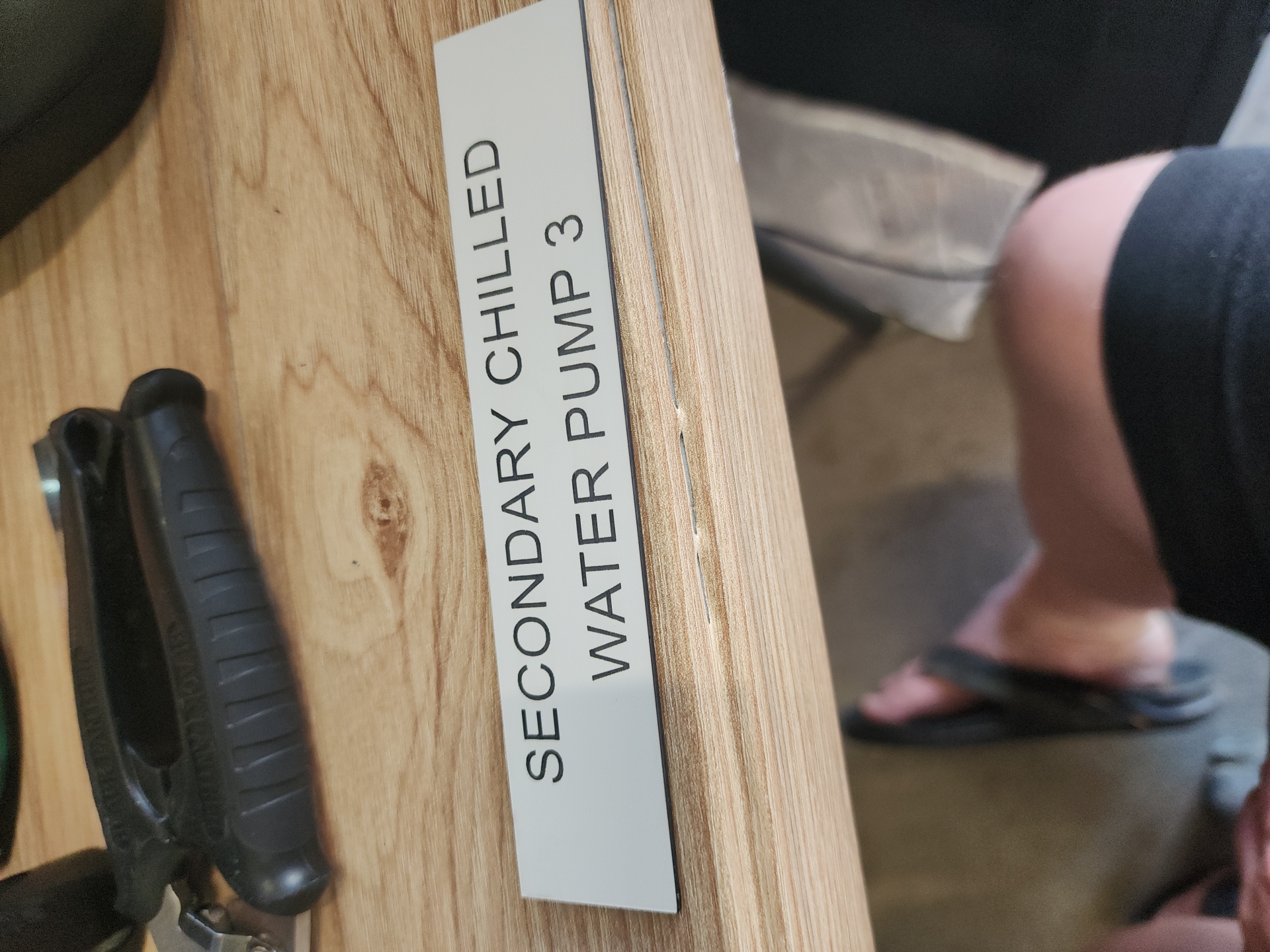 Engraved equipment label identifying a chilled water pump, mounted on plant machinery
